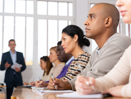Focused adult latin american man listening to lecture in classroom with group. Postgraduate education concept