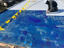 Air barrier being applied to low slope roofing