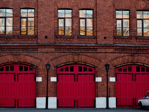 A fire station with a wooden red gate and a car nearby.