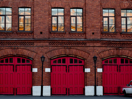 A fire station with a wooden red gate and a car nearby.