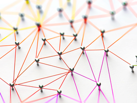 Linking entities. Networking, social media, SNS, internet communication abstract. Small network connected to a larger network. Web of red, orange and yellow wires on white background. Shallow DOF.