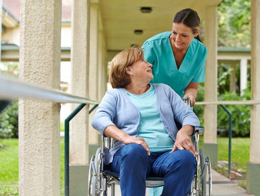 Senior woman in wheelchair talking to a nurse in a hospital garden