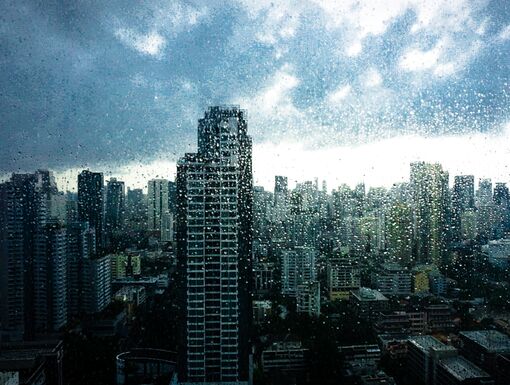 Rainy season, Rain drops on window's glass is viewing the downtown city skyline on a dark weather day. Abstract rain drop/raining scenery background - can be used for display or montage your products.