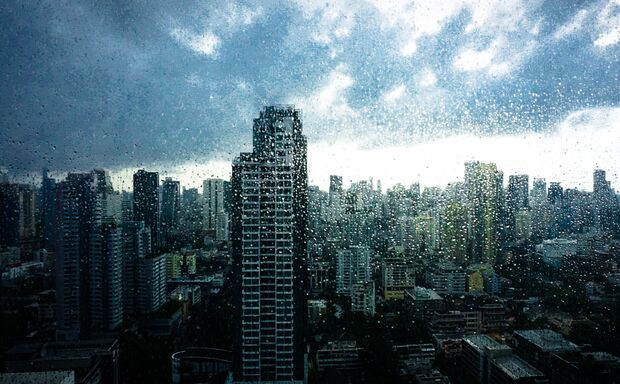Rainy season, Rain drops on window's glass is viewing the downtown city skyline on a dark weather day. Abstract rain drop/raining scenery background - can be used for display or montage your products.