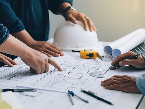Engineer or architect meeting for project working with partner and checks construction blueprints on new project with engineering tools in working site.